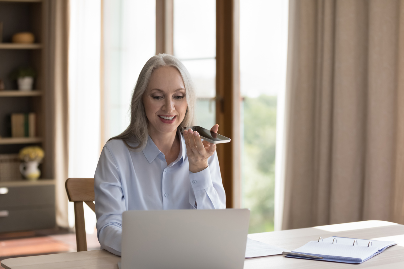 Happy grey haired freelance business lady using virtual assistant